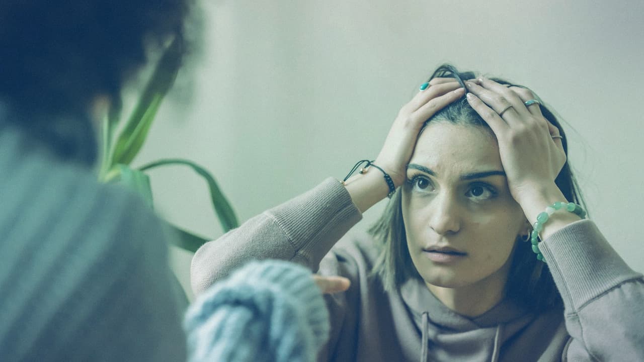 زن مضطرب با دستان روی سر و چهرهٔ نگران، نماد تنش اضطراب