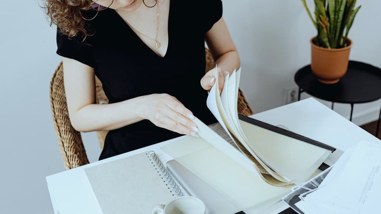 زن پشت میز در حال مرور دقیق پوشه و اسناد، نماد کمال‌گرایی و نظم سخت