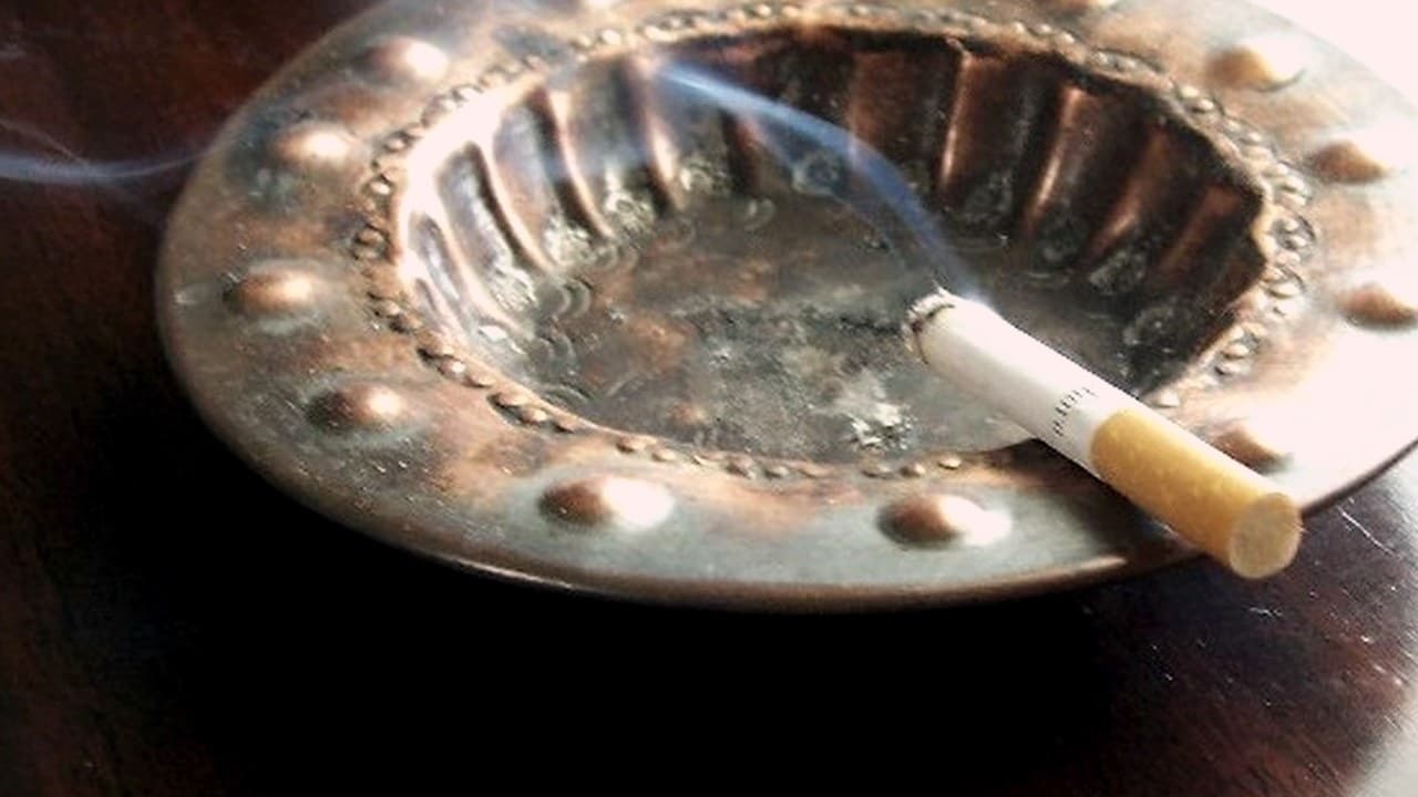 سیگار روشن روی زیرسیگاری فلزی، نماد نیکوتین و ترک سیگار در دوره بهبودی
